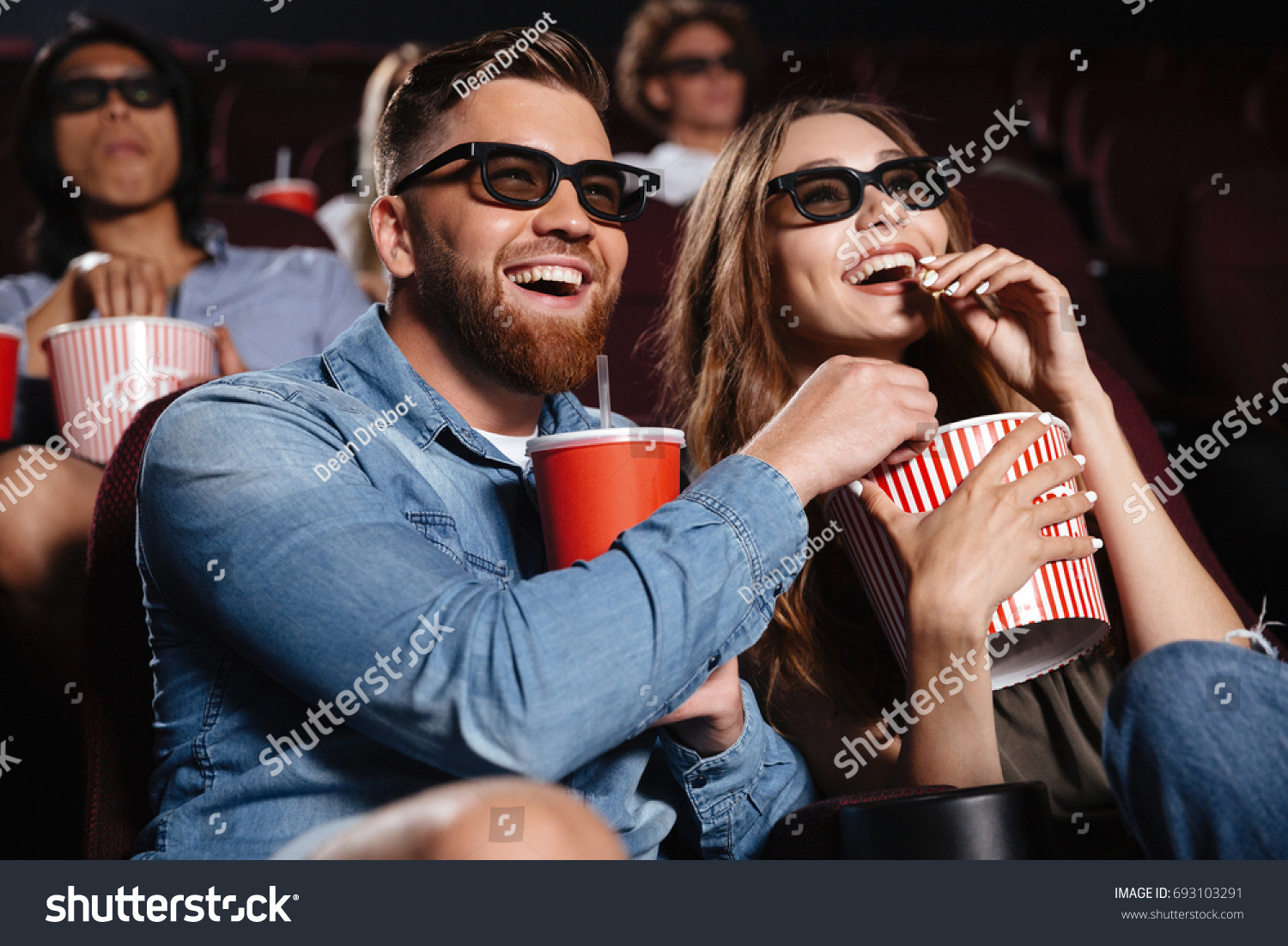 stock-photo-picture-of-happy-friends-sitting-in-cinema-watch-film-eating-popcorn-and-drinking-aerated-sweet-693103291